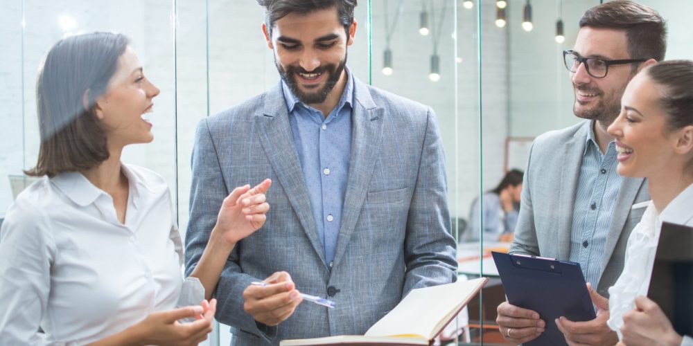 Business team discussing business documents, standing in the office lobby Business team discussing business documents, standing in the office lobby